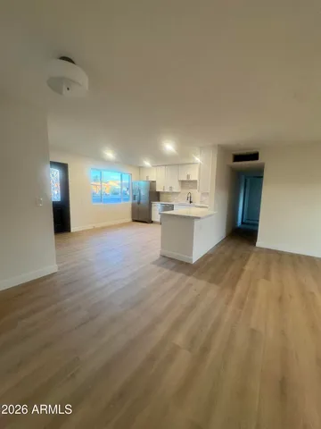 a view of a big room with wooden floor and windows