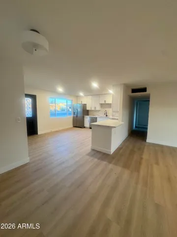 a view of an empty room with a window and wooden floor