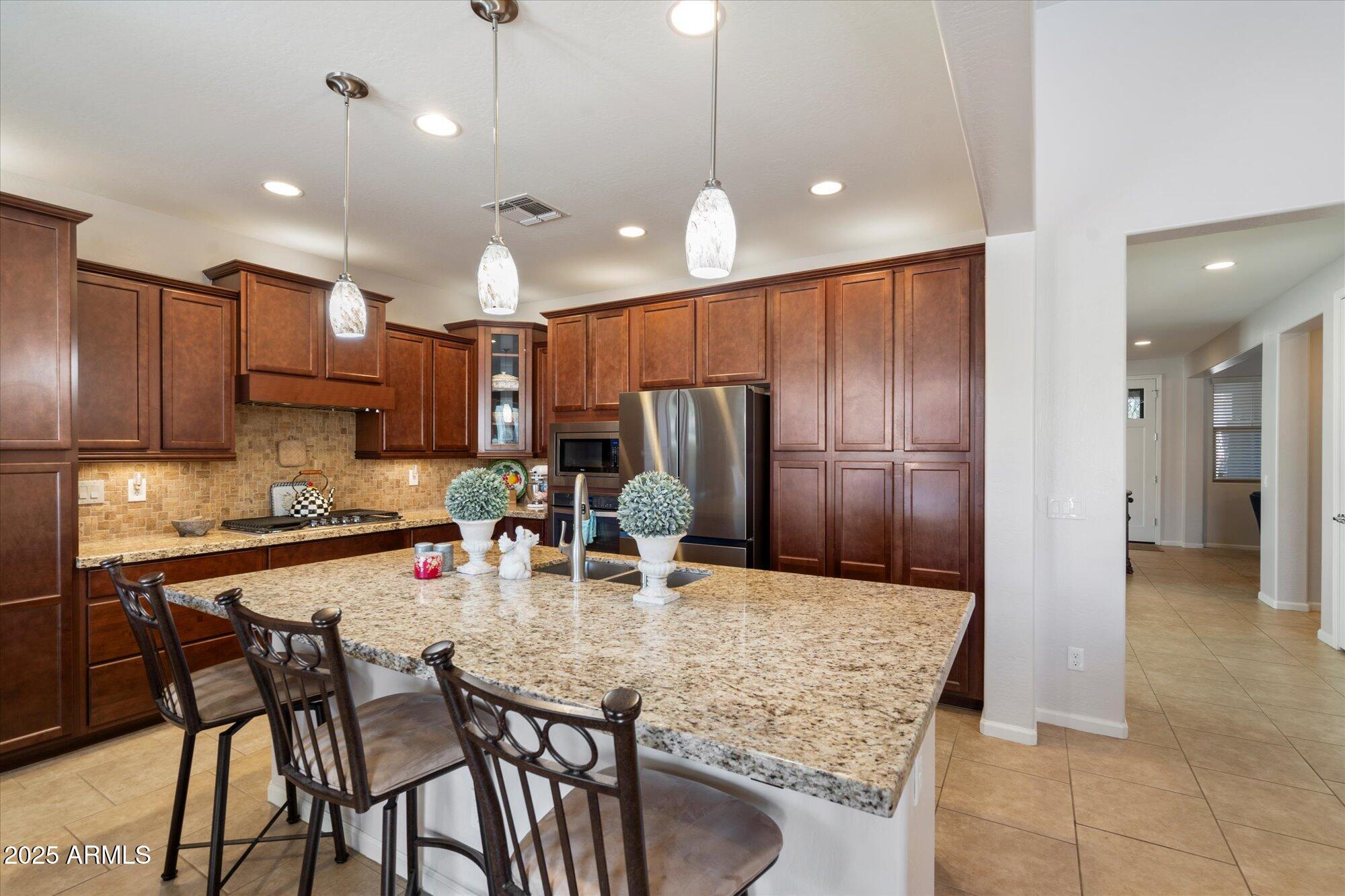 9010 West Ruth Avenue Peoria, AZ 85345 - Photo 11 of 26 a kitchen with stainless steel appliances granite countertop a kitchen island a table and chairs in it