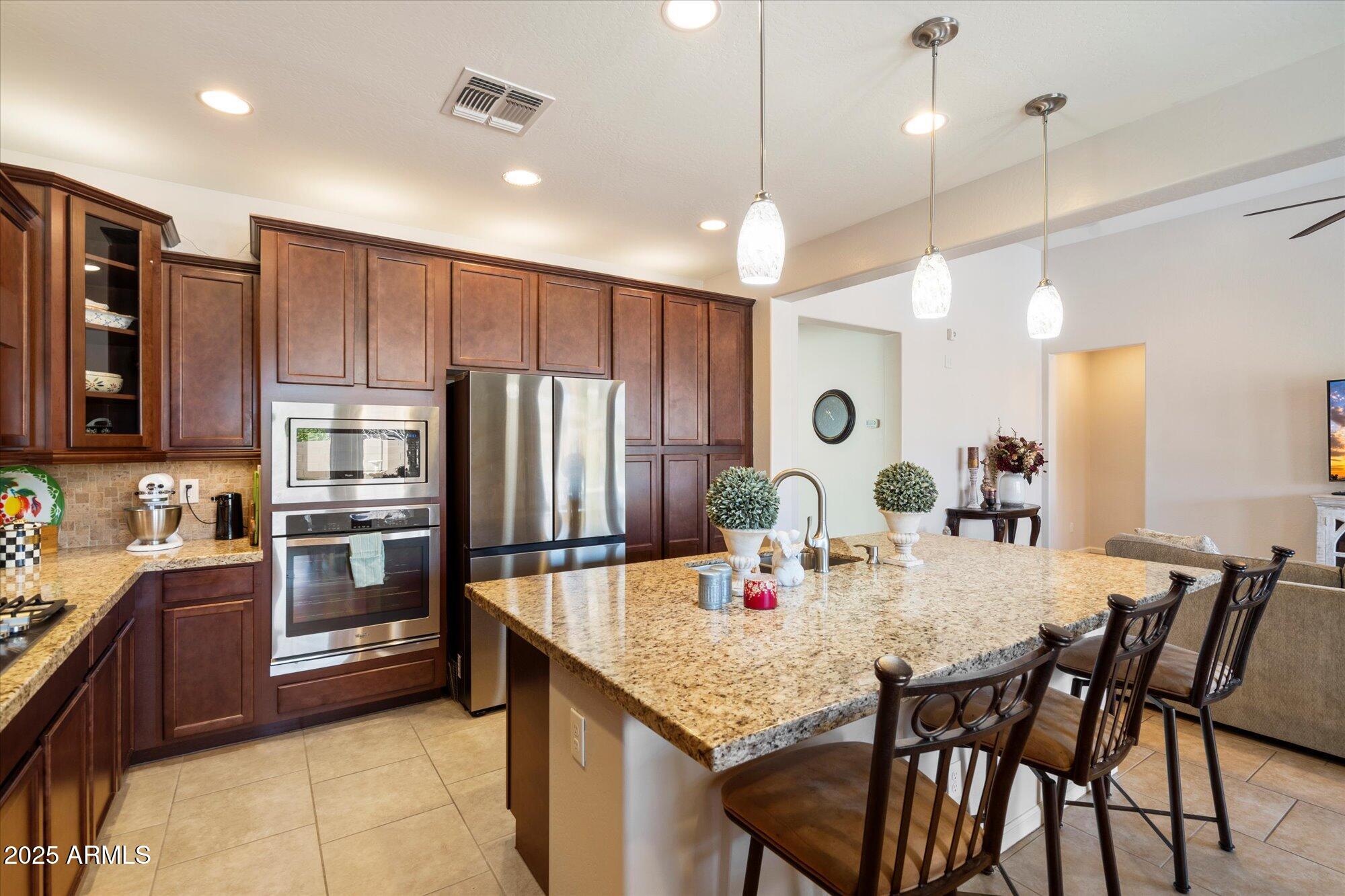 9010 West Ruth Avenue Peoria, AZ 85345 - Photo 10 of 26 a kitchen with stainless steel appliances kitchen island granite countertop a kitchen island a stove a dining table and chairs