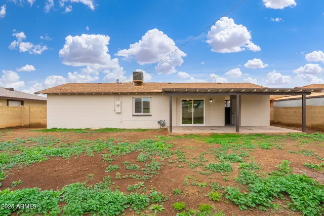 a backyard of a house with table and chairs plants and large tree