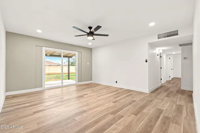 a view of an empty room with a window and wooden floor
