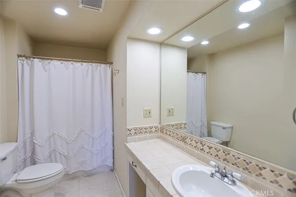 a bathroom with a granite countertop sink a toilet and shower