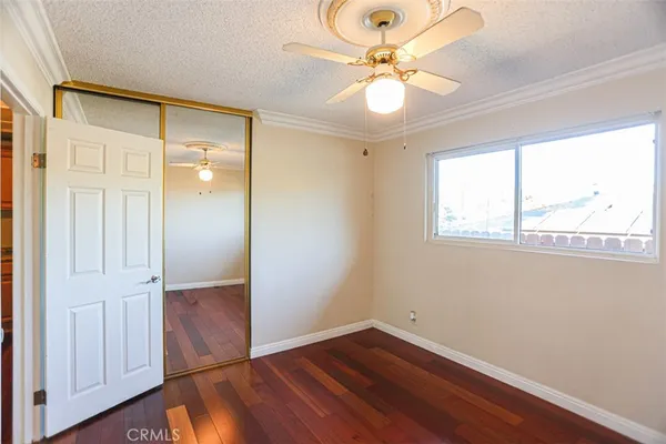 an empty room with wooden floor fan and windows