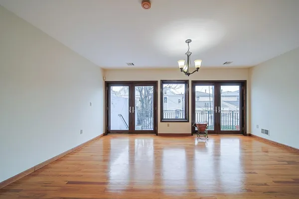 a view of an empty room with window and wooden floor