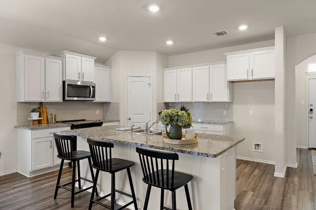 a kitchen with granite countertop a table chairs microwave and sink