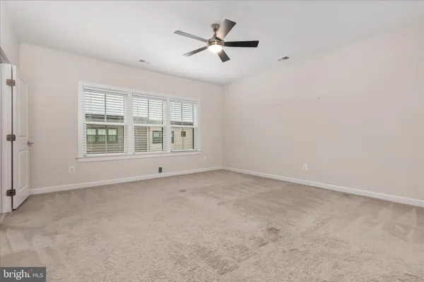 an empty room with chandelier fan and windows