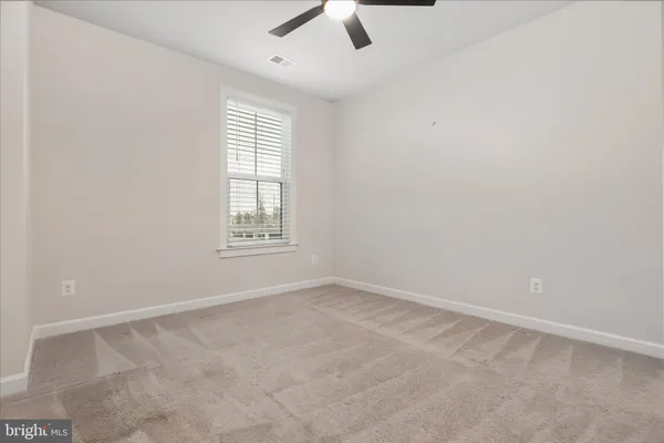 an empty room with a window and a ceiling fan