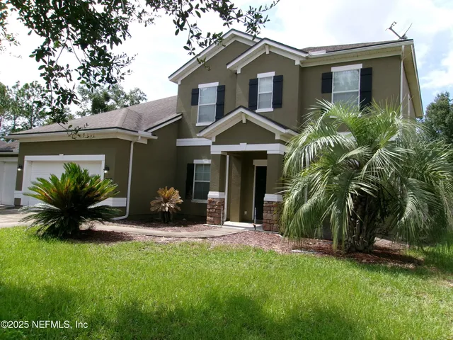 a front view of a house with a garden and plants
