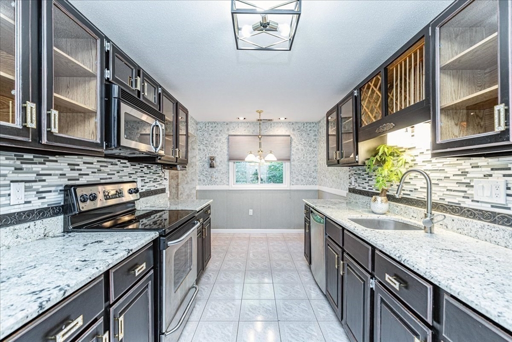 9 Ledgewood Way, Unit 9 Peabody, MA 01960 - Photo 18 of 42 a kitchen with stainless steel appliances granite countertop a sink stove and cabinets