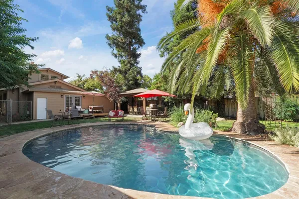 a backyard of a house with table and chairs potted plants and a large tree