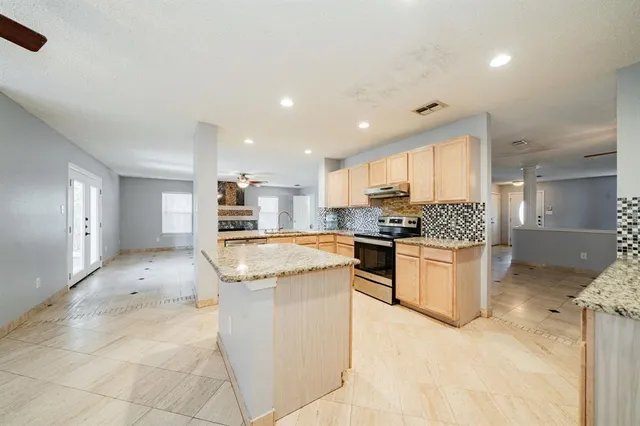 a kitchen with stainless steel appliances granite countertop a stove top oven a sink a refrigerator and white cabinets