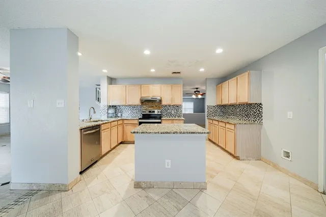 a kitchen with granite countertop a sink stainless steel appliances and white cabinets