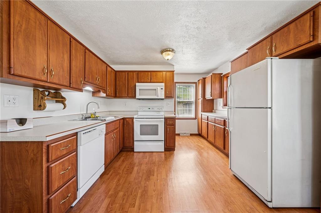 1813 Service Lane Monessen, PA 15062 - Photo 12 of 31 a kitchen with stainless steel appliances granite countertop a refrigerator a sink dishwasher a stove and white countertops with wooden floor