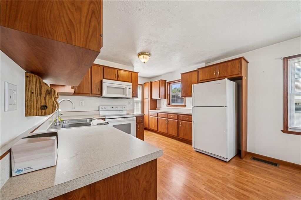 1813 Service Lane Monessen, PA 15062 - Photo 15 of 31 a kitchen with a refrigerator a stove a microwave and wooden floor