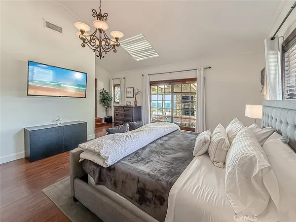 a bedroom with a bed and a dresser with wooden floor