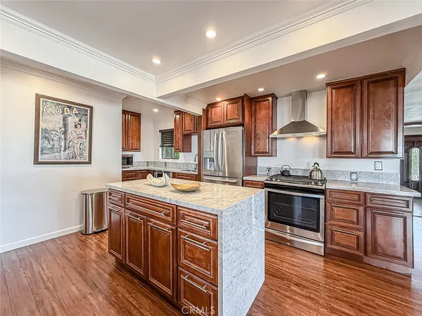 a kitchen with stainless steel appliances granite countertop a stove a sink dishwasher and a refrigerator with wooden floor