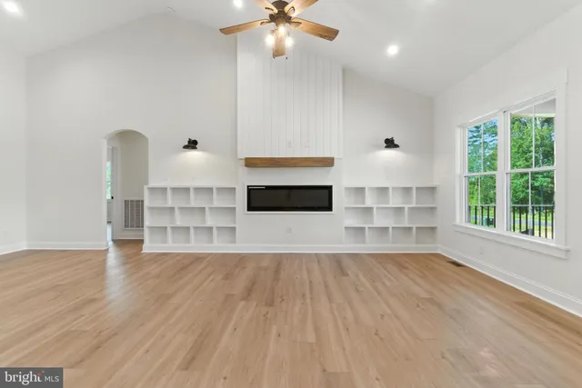 an empty room with wooden floor fireplace and windows