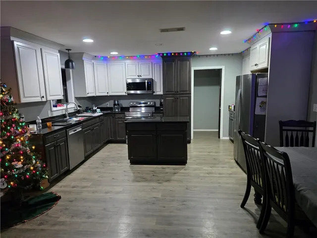 a kitchen with stainless steel appliances granite countertop a stove top oven a sink dishwasher a dining table and chairs with wooden floor