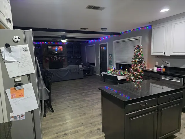 a kitchen with kitchen island granite countertop a sink dishwasher and a stove with wooden floor