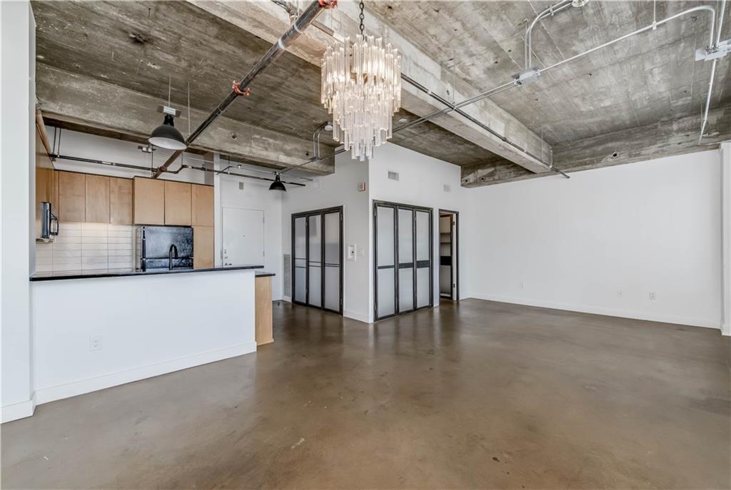 710 Colorado Street, Unit G9 Austin, TX 78701 - Photo 10 of 25 Industrial chic living space featuring a concrete ceiling with exposed pipes, complemented by a kitchen with sleek cabinetry.