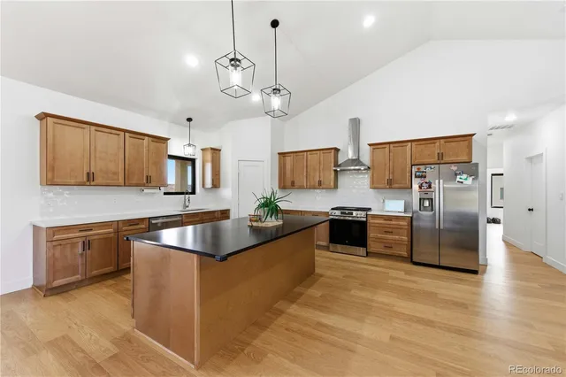 a kitchen with stainless steel appliances granite countertop a sink a stove and a wooden floors