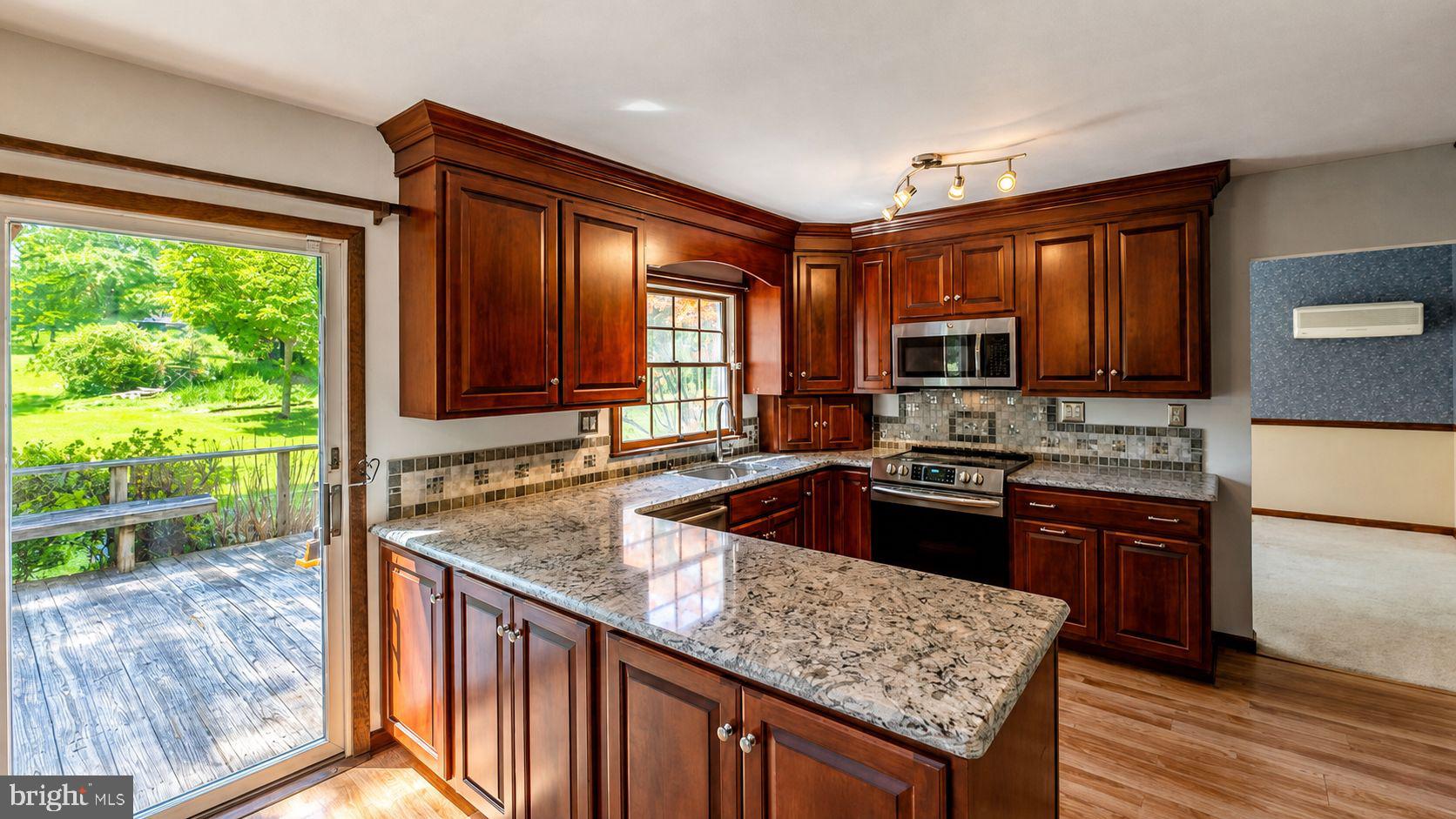 223 Trythall Road Elverson, PA 19520 - Photo 22 of 78 a kitchen with granite countertop wooden cabinets a stove a sink and a large window