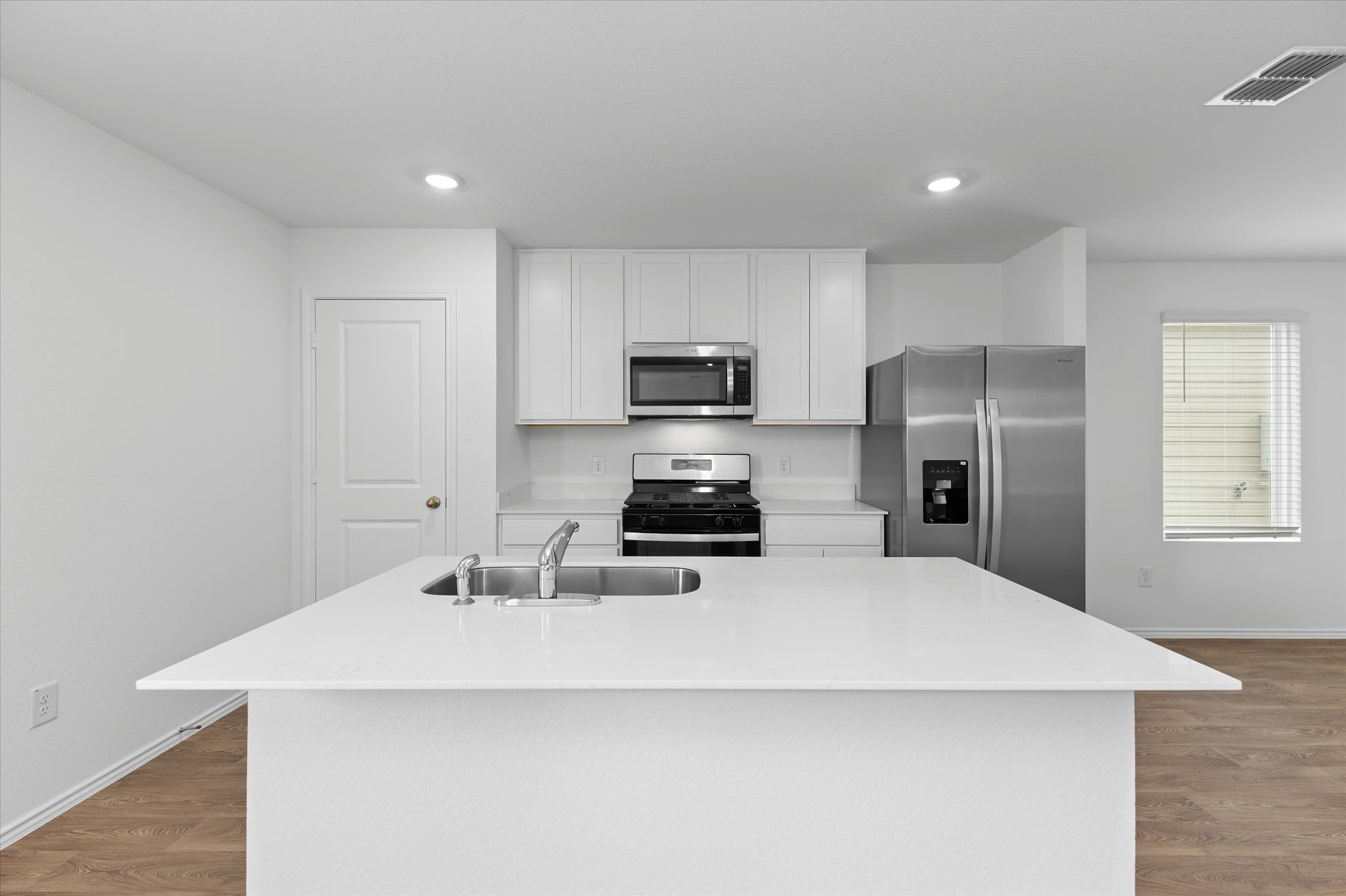 456 Sandringham Loop Kyle, TX 78640 - Photo 32 of 40 A well-equipped kitchen boasts stainless steel appliances, pristine white cabinetry, and an island with a sink.