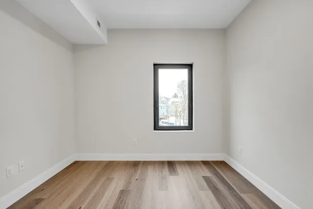 a view of a small space with wooden floor and a window