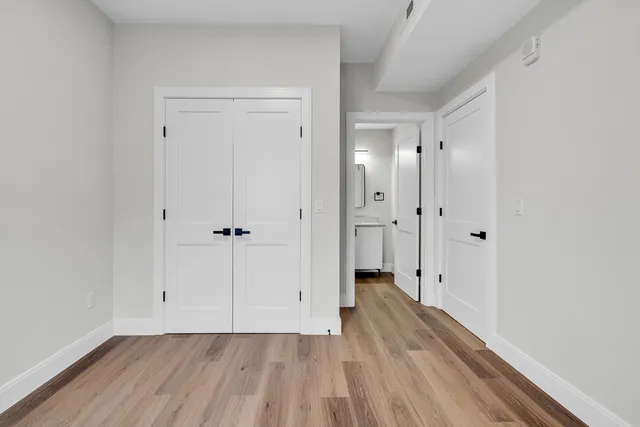a view of a hallway with wooden floor and a bathroom