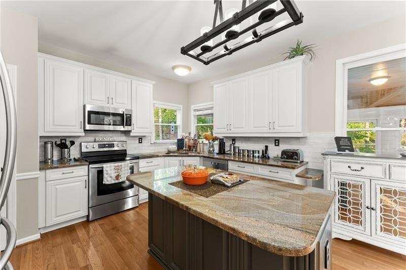 385 Graves Road Acworth, GA 30101 - Photo 4 of 61 a kitchen with stainless steel appliances granite countertop a stove top oven a sink a refrigerator white cabinets and wooden floor