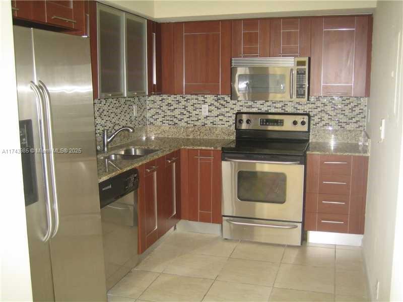 a kitchen with stainless steel appliances granite countertop a stove a refrigerator and a microwave