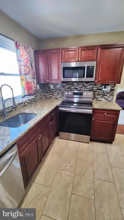 a kitchen with stainless steel appliances granite countertop a sink stove and cabinets