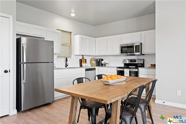 a kitchen with stainless steel appliances a refrigerator a stove a dining table and chairs