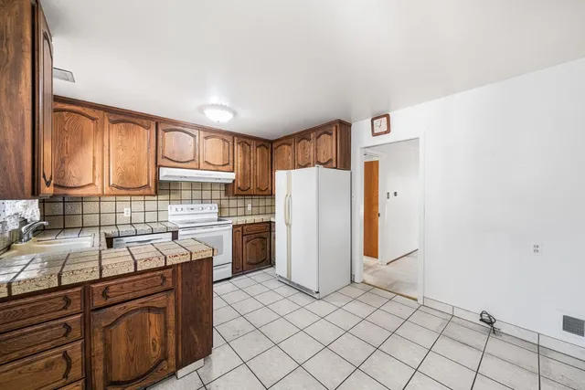 a kitchen with granite countertop a refrigerator and a sink