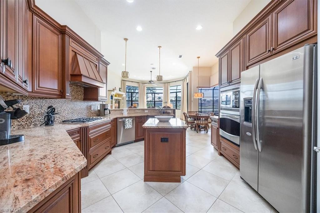 6504 Costa Circle Naples, FL 34113 - Photo 7 of 25 Kitchen with a center island, custom exhaust hood, recessed lighting, backsplash, and appliances with stainless steel finishes
