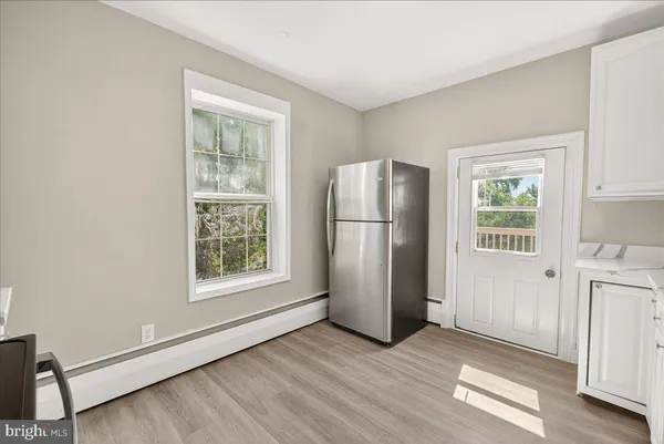 an empty room with windows and refrigerator