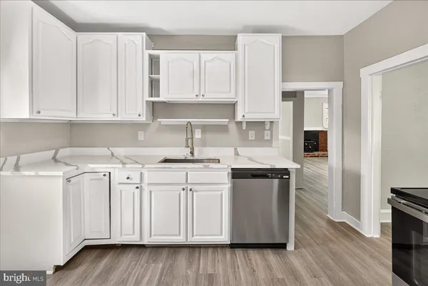 a kitchen with stainless steel appliances granite countertop a sink and cabinets with wooden floor