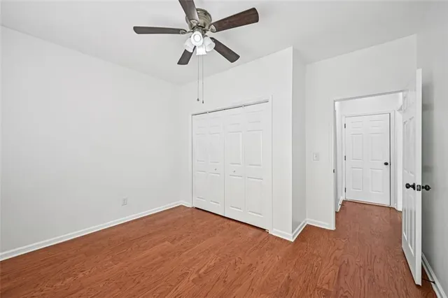 an empty room with wooden floor ceiling fan and windows