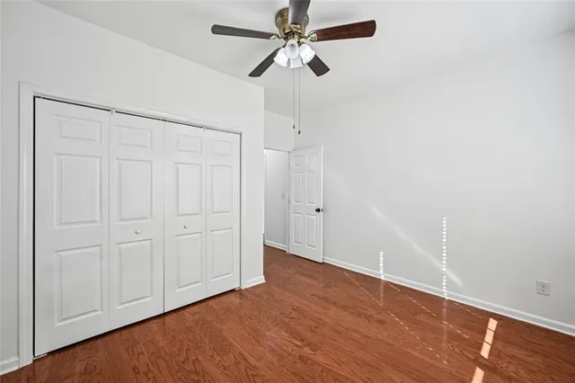 an empty room with wooden floor ceiling fan and windows