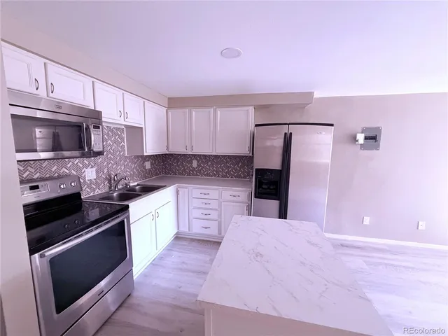 a kitchen with granite countertop a stove microwave and refrigerator