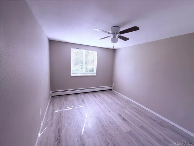 an empty room with wooden floor chandelier fan and windows