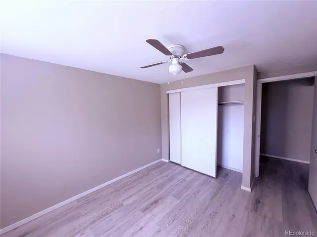 an empty room with wooden floor and a ceiling fan