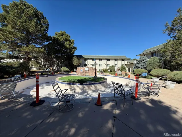 a view of a swimming pool with lawn chairs and potted plants