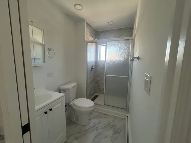 a bathroom with a granite countertop toilet a sink a shower and a mirror