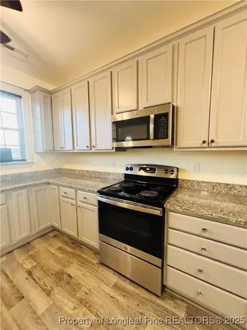 a kitchen with granite countertop a stove microwave and cabinets