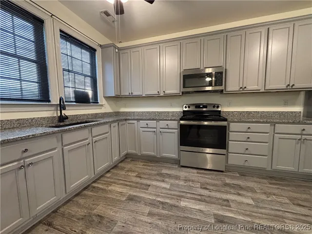 a kitchen with stainless steel appliances granite countertop a stove a sink and a microwave