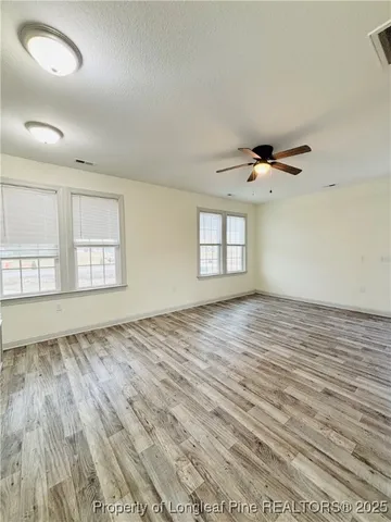 a view of empty room with wooden floor and fan