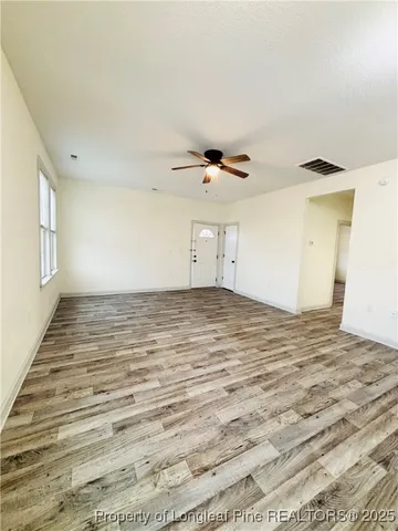 a kitchen with granite countertop a refrigerator oven a sink dishwasher and white cabinets with wooden floor