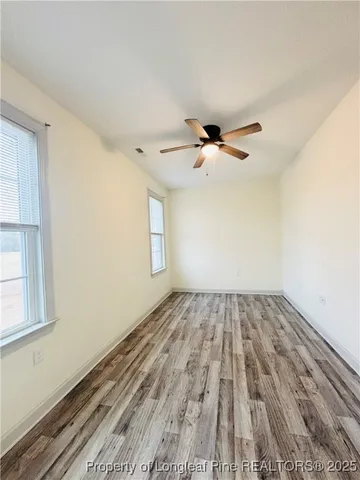 a view of empty room with wooden floor and fan